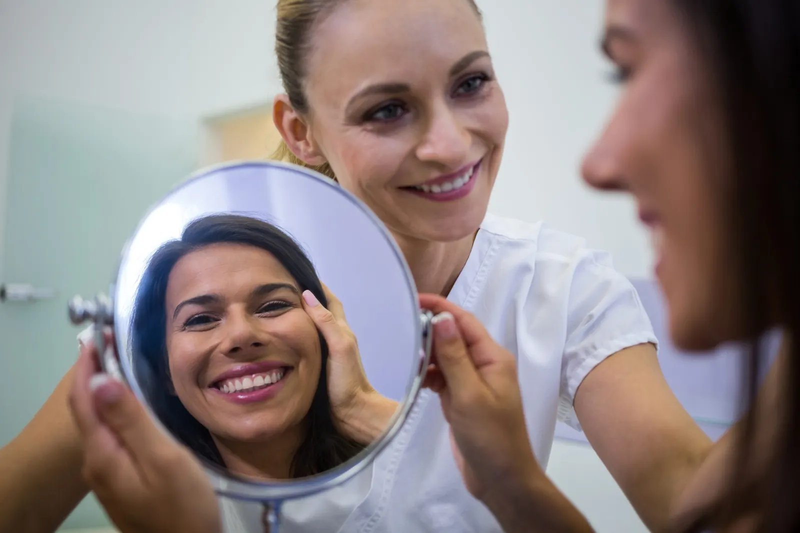 Client smiling at her results in a hand mirror